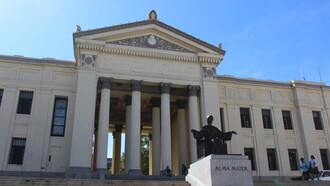 El monumento a la entrada de la Universidad de La Habana representa a la Alma Mater. Esta escultura de bronce, creada en 1919 por el artista checo Mario Korbel, simboliza la "madre nutricia" del conocimiento. La figura femenina está inspirada en los rasgos de una joven cubana llamada Feliciana Villalón, La Habana, Cuba