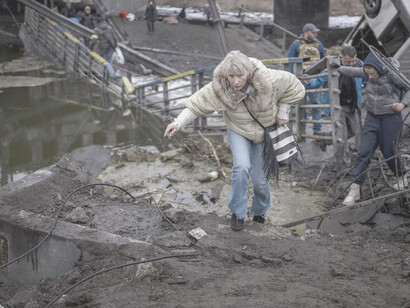 Mujer cruza un puente para unirse al grupo de civiles que huirán de Ucrania como refugiados 