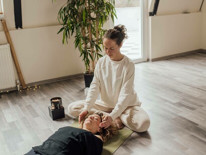 A woman places her hands near the skull of her client in an attempt to heal her