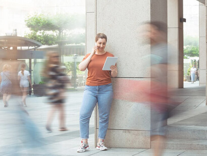A woman on a busy urban street, engaged in a phone call amidst swift-moving pedestrians, capturing the essence of modern society's relentless pace and the significance of time