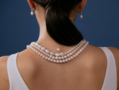 Mulher com colares e brincos de pérolas. As pérolas estão a viver um renascimento na moda contemporânea, sendo incorporadas em designs modernos e arrojados