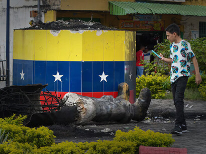 A young man takes a picture of a destroyed statue