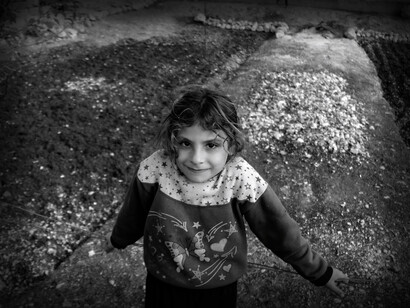 A young girl refugee tries to smile while her family seeks asylum in Idlib refugee camp, Idlib Governorate, Syria