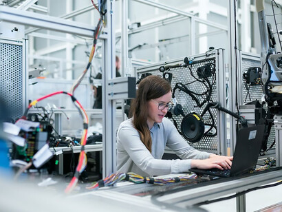 In the workshop, a female engineer adeptly engages in her tasks, seamlessly navigating through the machinery with a blend of proficiency and dedication