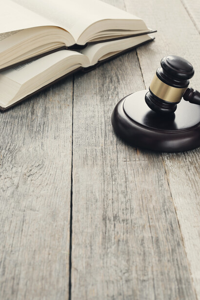 Mazo judicial apoyado en una mesa con libros