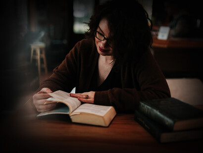 Mujer revise las referencias de un libro en una biblioteca