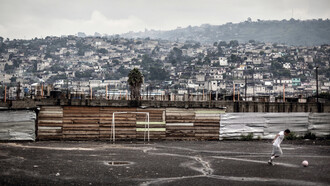 Joven jugando fútbol en un barrio marginal de Latinoamérica