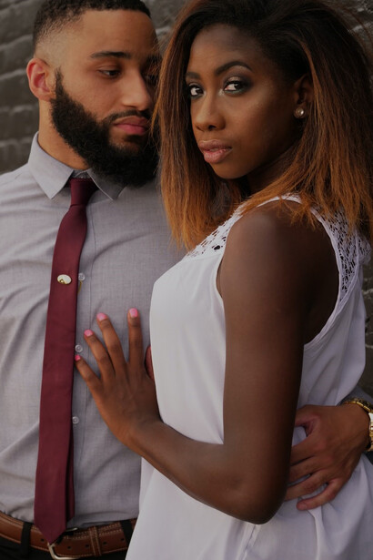 A man gazing intently at a woman beside a gray concrete wall