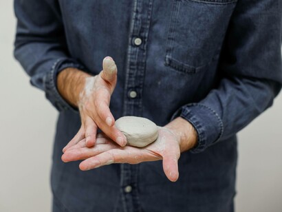 A man gently taps his piece of clay to make it perfect in their eyes  