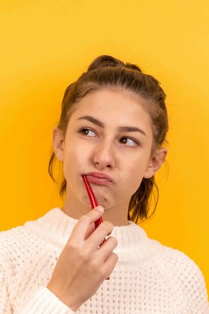 Teenage girl thinking while brushing her teeth