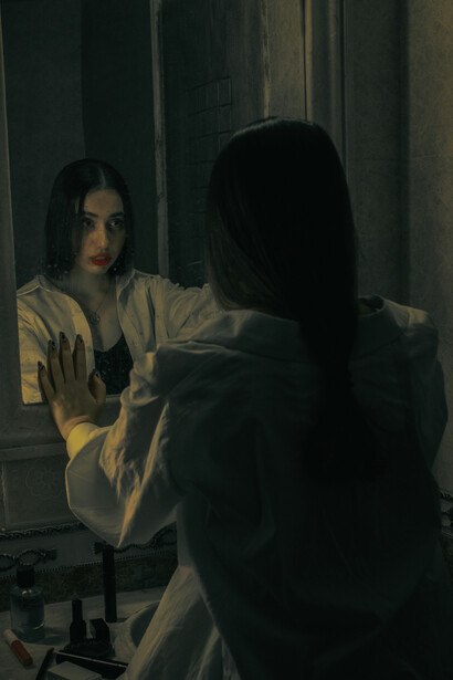 A solitary woman gazing at her reflection in the mirror, her sadness written across her face