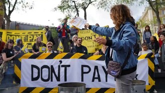 A volunteer burns currency in the protest against rising costs of living at King’s Cross in London