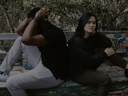 A couple is fighting, they sit back to back on the bench