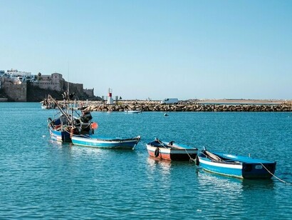 Fishing vessels gently floating on Bouregreg River, reflecting the natural landscape that influenced one of Zaha Hadid’s final masterpieces