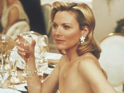 Samantha Jones from the television series Sex & the City is elegantly dressed and enjoying a cocktail at a reception party