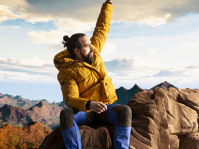 A lone traveler stands on a mountain summit, soaking in the breathtaking view of the peaks