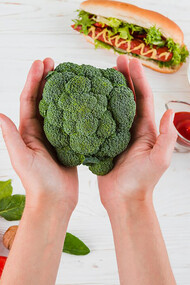A hand holding fresh broccoli, a symbol of healthy eating and nutritional vitality