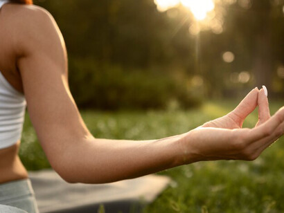 A woman meditating in nature, harnessing spiritual energy, with an aura of positive energy and a flowing sense of inner strength