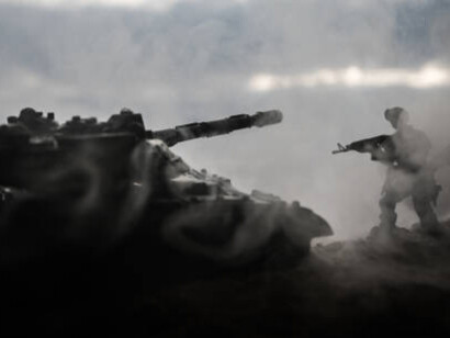 Silhouettes of World War II soldiers and armored vehicles appear in a battle scene under a foggy, war-torn sky at sunset