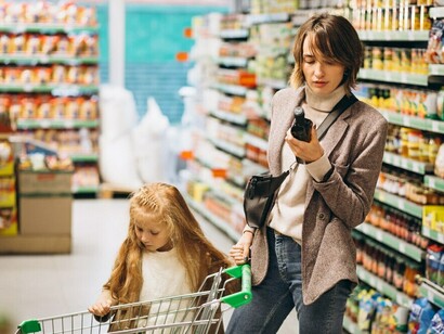 A mother and daughter reading food labels together at the grocery store