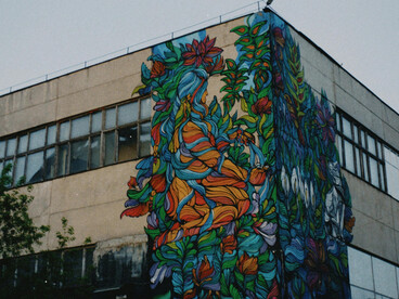 A weathered city building covered in graffiti under a cloudy sky