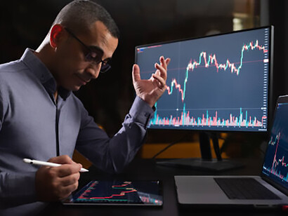Late-night stock market monitoring: exhausted man checks exchange on laptop