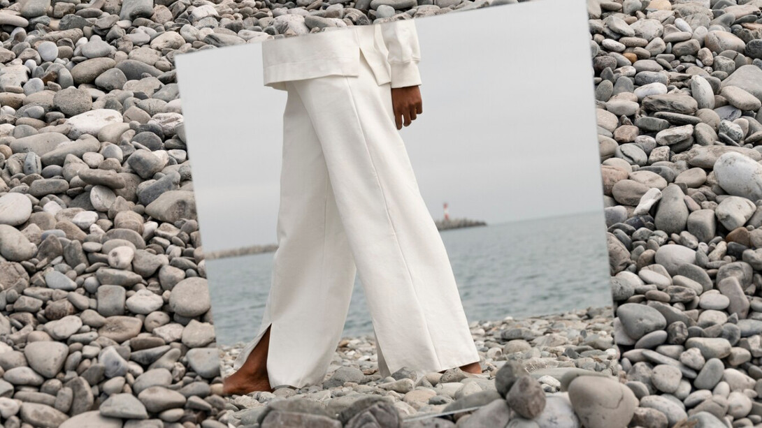 Barefoot on the rocks, a model steps into herself grounded in reflection and free to feel