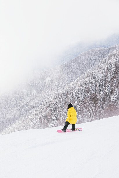 A woman on her snowboard looking to the beauty of the snow covering everything she sees