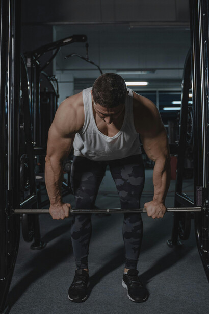 A muscular man lifting a barbell in the gym, captured mid-training session