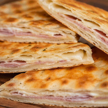 Crescia Sfogliata. Specialità dell'entroterra pesarese, caratterizzata da sottili strati fragranti che racchiudono il gusto autentico della tradizione contadina