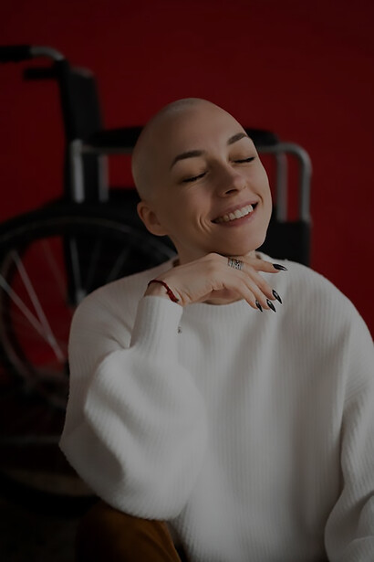 In a powerful display of strength, a woman facing cancer strikes a positive pose beside her wheelchair, embodying resilience and optimism in the midst of her challenging journey