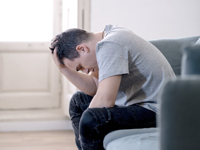 Hombre apático sentado en un sofá: procrastinar es dejar algo para más adelante, mientras que la acrasia, sería pensar que uno «debiera» hacer algo sin hacerlo