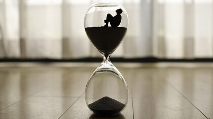 An hourglass resting on the floor, time slipping away, a poignant symbol of life's transience