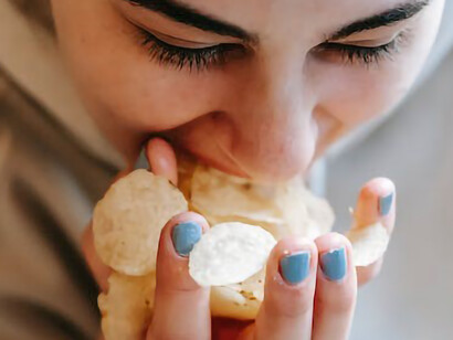 The girl indulges in potato chips, savoring each bite with her hands