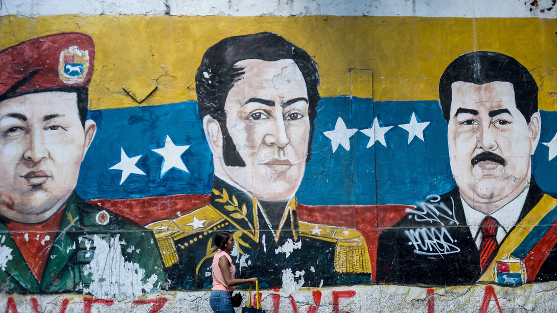 Una mujer en Caracas pasa delante de un mural con los rostros de Chávez, Bolívar y Maduro