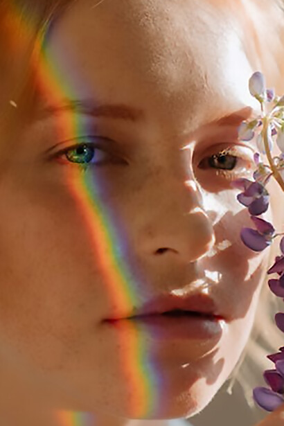 A captivating image featuring a beautiful woman with a rainbow gracefully arching over her eyes on the right side of her face