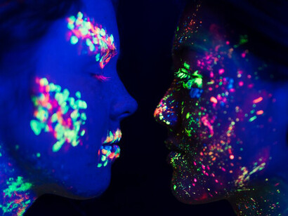 Highly detailed close-up of a woman adorned with vibrant fluorescent makeup, showcasing abstract colors and evoking powerful emotions