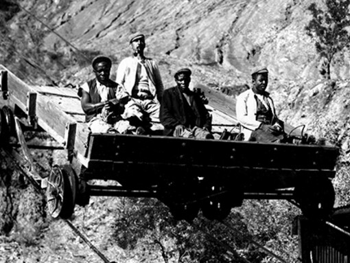 Four miners riding a transport vehicle in an open-pit diamond mine, illustrating transport methods in Kimberley, South Africa, 1800s