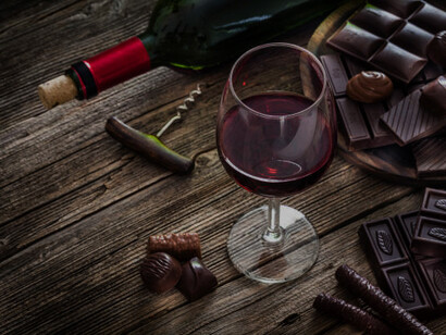 Glasses of red wine paired with chocolate truffles on a rustic wooden table