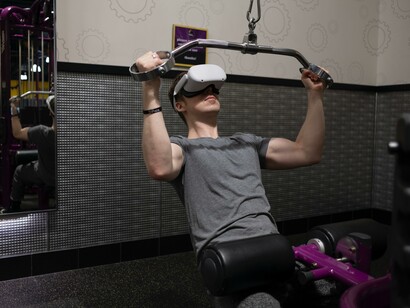Wellness metaverse: man doing a shoulder workout with virtual reality gear