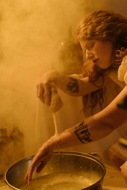 A woman stands in a bathroom, washing her hands as part of a cleaning routine
