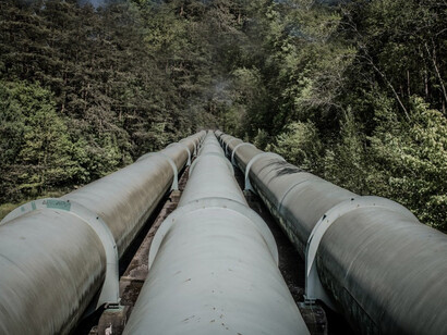 A large pipe sits next to a forest in Geesthacht, Germany, surrounded by summer energy, electricity, and lush trees