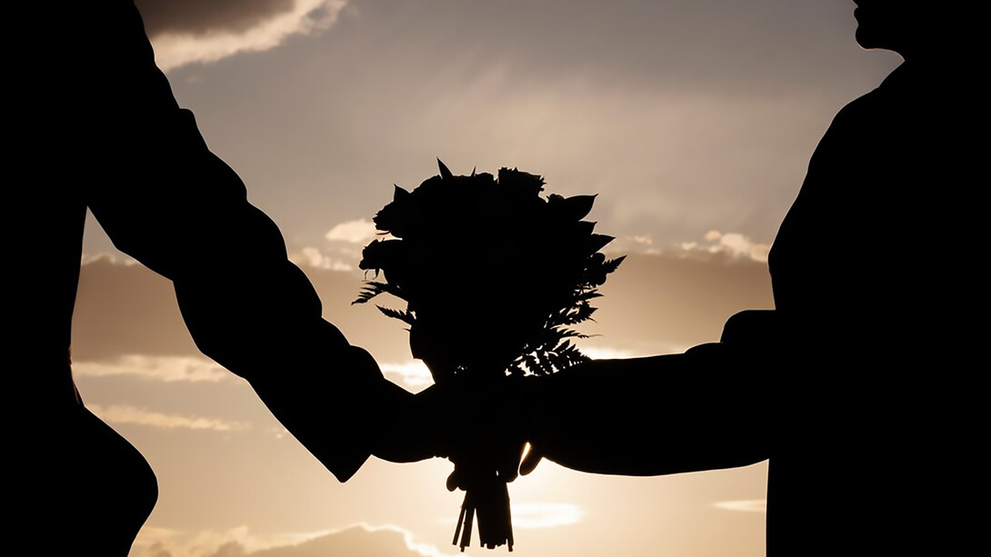 Side view of a couple holding a bouquet of flowers together