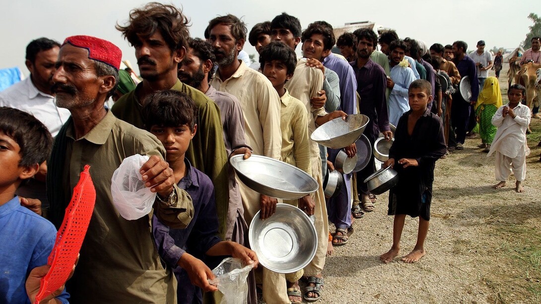 Pakistani people, standing in a line waiting to get some food. These people are facing anxiety and distress