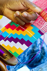 In the vibrant setting of Ghana in 2019, a shuttle skillfully maneuvers through the threads, contributing to the intricate artistry of Kente weaving, this snapshot captures the craftsmanship and tradition embedded in the process, where the shuttle becomes a symbol of the meticulous workmanship that brings the renowned Kente cloth to life
