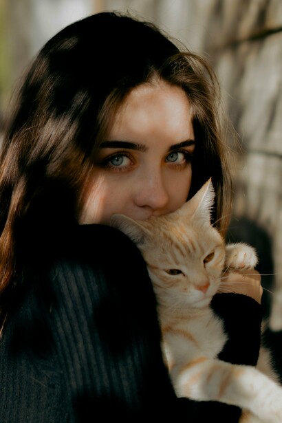 Mulher abraça um gato ruivo, em uma imagem que aproxima afeto e convivência entre pessoa e animal. No texto, o termo “gata” ganha um sentido figurado quando deixa de designar o animal e passa a caracterizar uma pessoa, mostrando como o contexto pode transformar o sentido das palavras