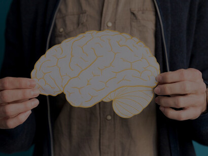 A close-up of a person pointing at a paper brain underscores important information about brain health and stroke recovery