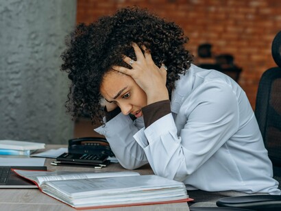 A woman coping with mounting stress at her desk, reflecting the connection between mental strain and the nervous system