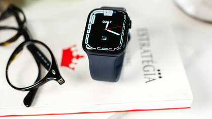 Smartwatch, óculos de leitura, livro sobre estratégia de escrita para copywriting sob mesa de uma especialista em marketing digital