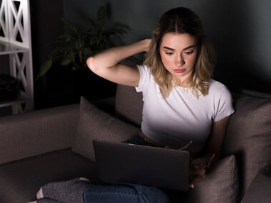 Overwhelmed by tasks, a woman works remotely on her laptop, reflecting the struggle to balance work and personal life